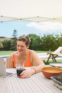 Smiling woman using laptop during vacation