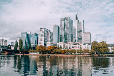 Buildings by river against sky in city