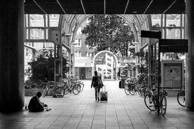 Rear view of woman walking with luggage at railroad station