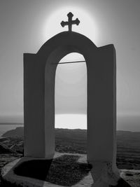 Cross on beach against sky