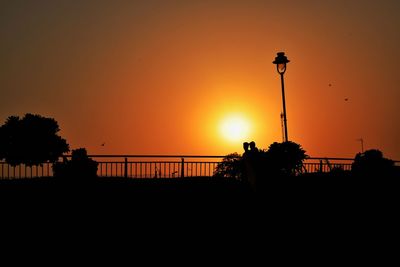 Silhouette people overlooking calm sea at sunset