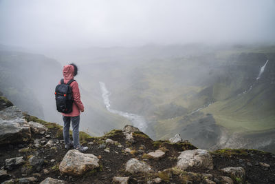 Man standing on mountain during foggy weather