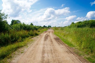 Road amidst field against sky