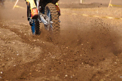 Low section of man riding motorcycle in motocross race on mud
