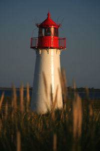 Red and white lighthouse at sky during sunset