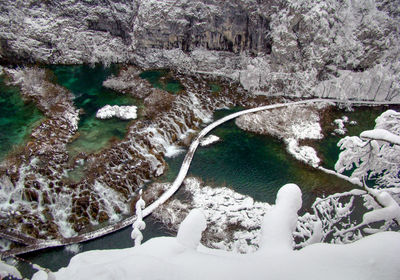 High angle view of frozen river amidst trees during winter