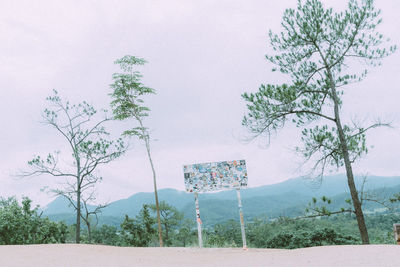 Road by trees on field against sky