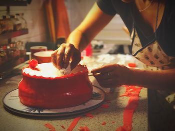 Midsection of woman preparing cake in kitchen