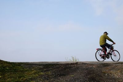 Rear view of man riding bicycle on road