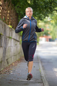 Portrait of woman running on footpath