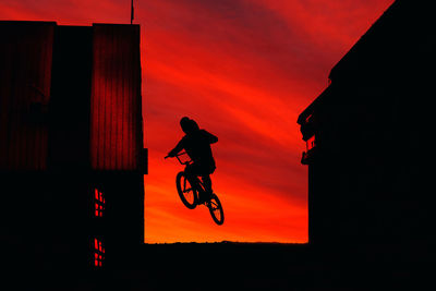 Silhouette man jumping against sky during sunset