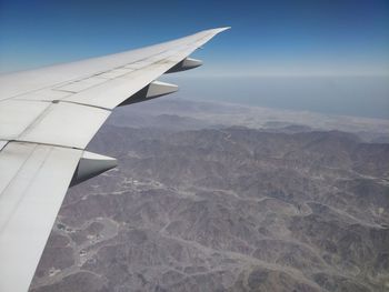 Airplane flying over landscape against sky