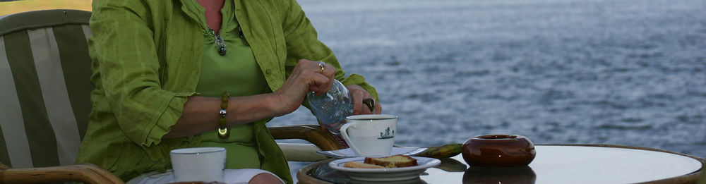 Midsection of woman having breakfast against sea