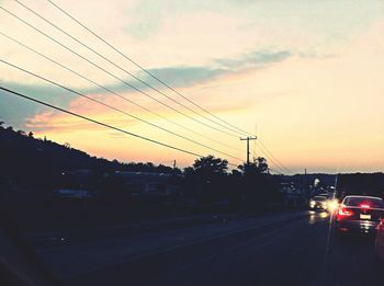 Cars on road against sky during sunset