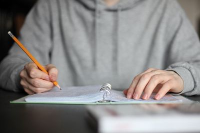 Midsection of man holding paper while sitting on table