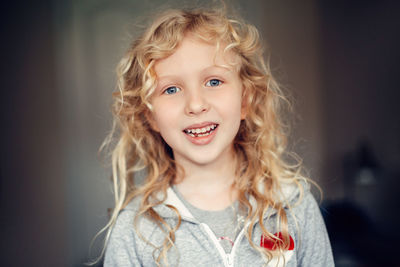 Portrait of smiling caucasian blonde girl with long messy hair. missing lost milk tooth.