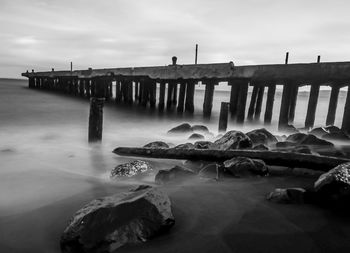 Wooden posts in sea against sky