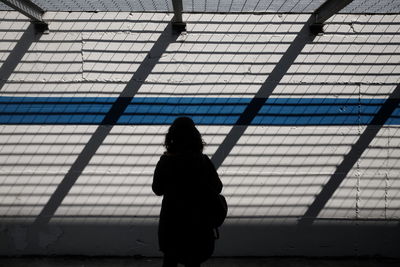 Rear view of silhouette woman standing against wall with shadow