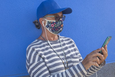 Portrait of woman using mobile phone against blue background