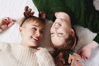High angle view of cheerful sisters wearing headbands while lying on rug
