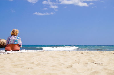 Rear view of man sitting on beach