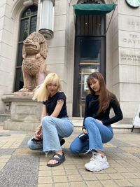 Full length of woman sitting against statue