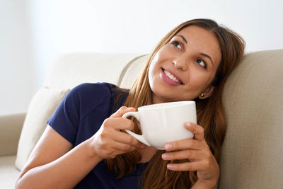 Portrait of smiling young woman drinking coffee
