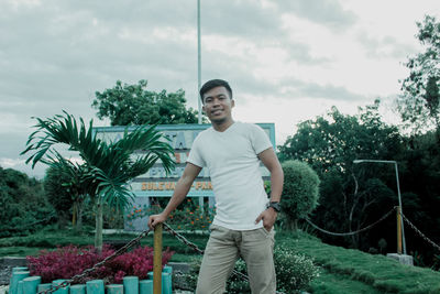 Portrait of young man standing against plants