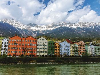 Houses by river and buildings against sky