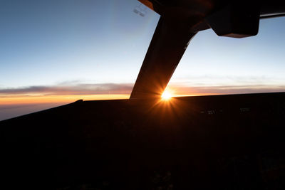 Cropped image of airplane wing against sky during sunset