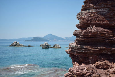 Scenic view of sea and mountains against clear blue sky