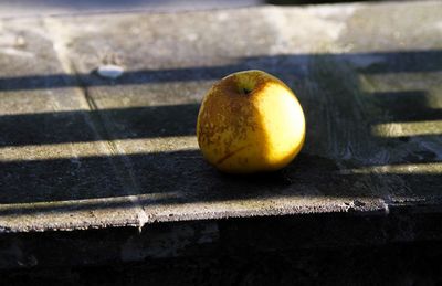 Yellow apple left on a marble bench.