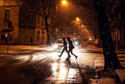 People walking on wet street at night