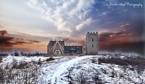 Snow covered old building against sky during sunset