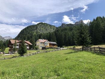 Houses on field by trees against sky