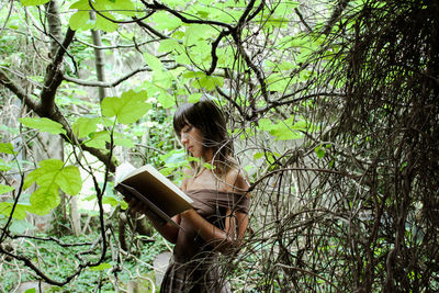 Young woman reading in a forest 