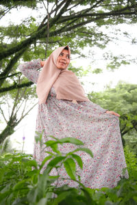 Woman standing by tree against plants