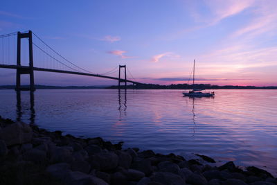 View of suspension bridge over sea during sunset