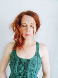 Portrait of beautiful young woman standing against white wall