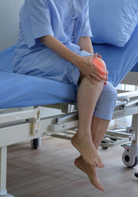 Low section of woman sitting on bed