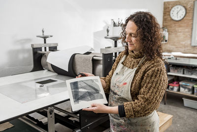 Female artist inspecting the results after operating a manual vi