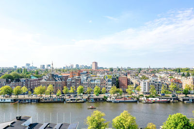 River by buildings in city against sky