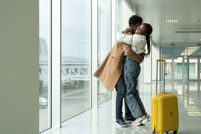 African man and woman hugging in airport. male giving female warm welcome embrace after travel