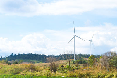 Wind turbines on field against sky