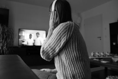 Rear view of woman sitting at home