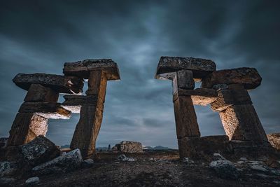 Low angle view of old ruins against cloudy sky