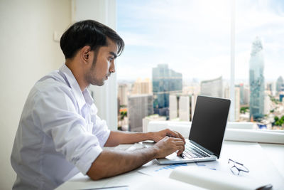 Man using mobile phone while sitting on table