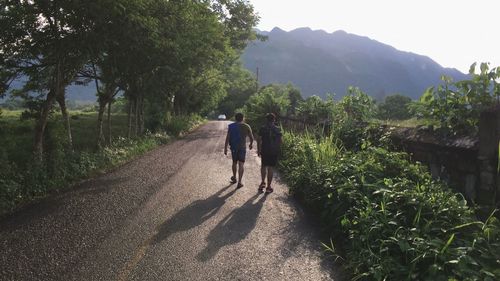 Rear view of men walking on road