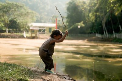 Rear view of young man jumping in lake
