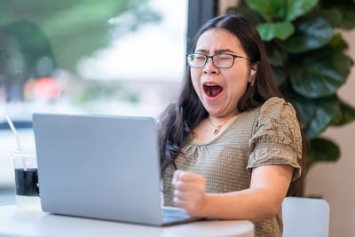 Young woman using phone while sitting on table